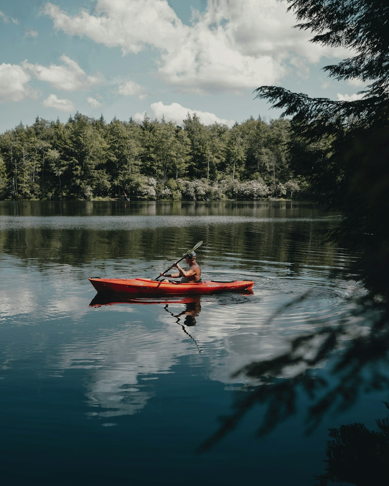 person riding red kayak on lake during daytime