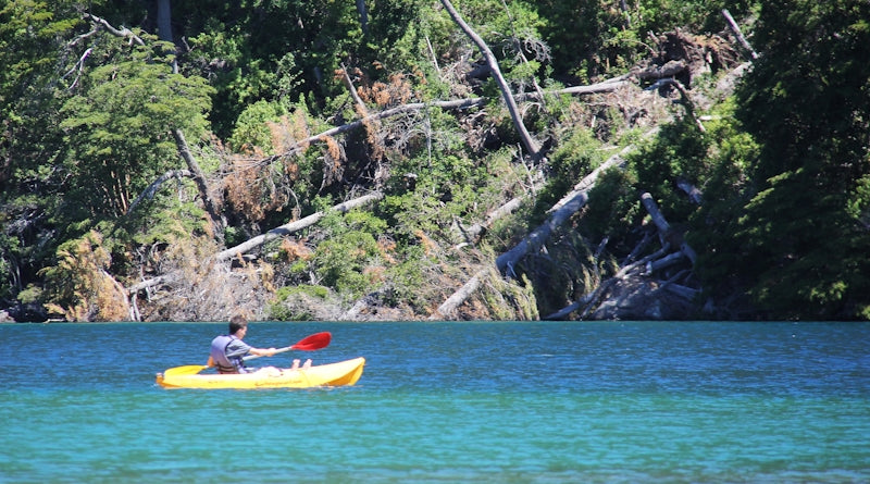 2 people riding on red kayak on body of water during daytime