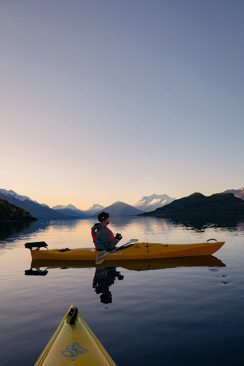 A man in a yellow kayak on a calm lake