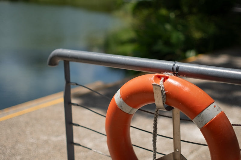 Orange life preserver attached to railing near water