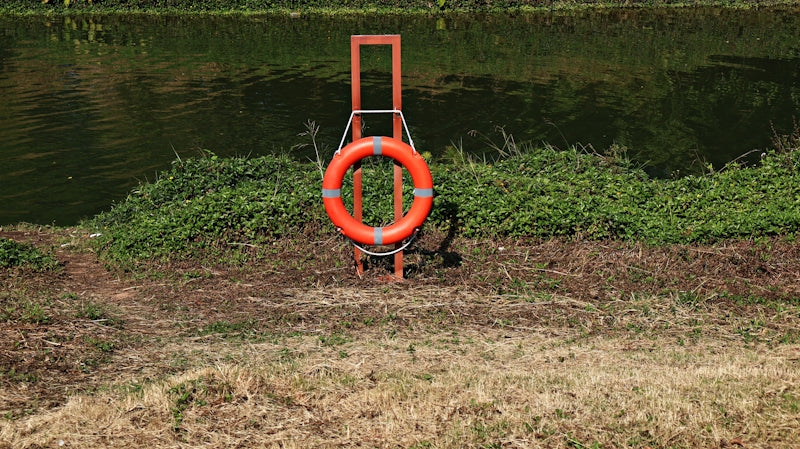 Orange life preserver on a stand by the water.