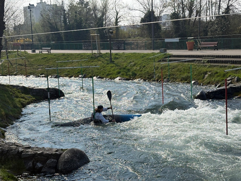 Person kayaking through whitewater rapids with gates.