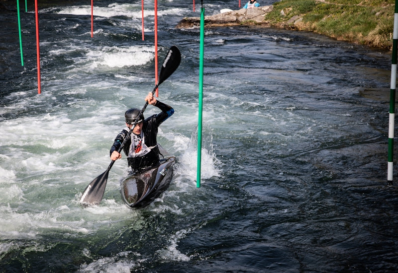 Man kayaking through whitewater rapids with gates