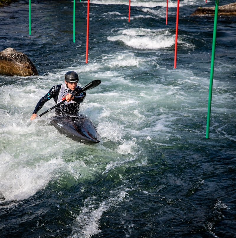 Man kayaking through whitewater rapids with gates