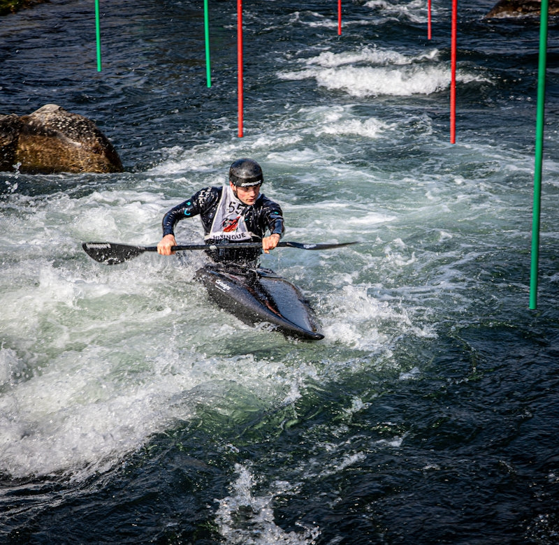 Man kayaking through whitewater rapids with gates